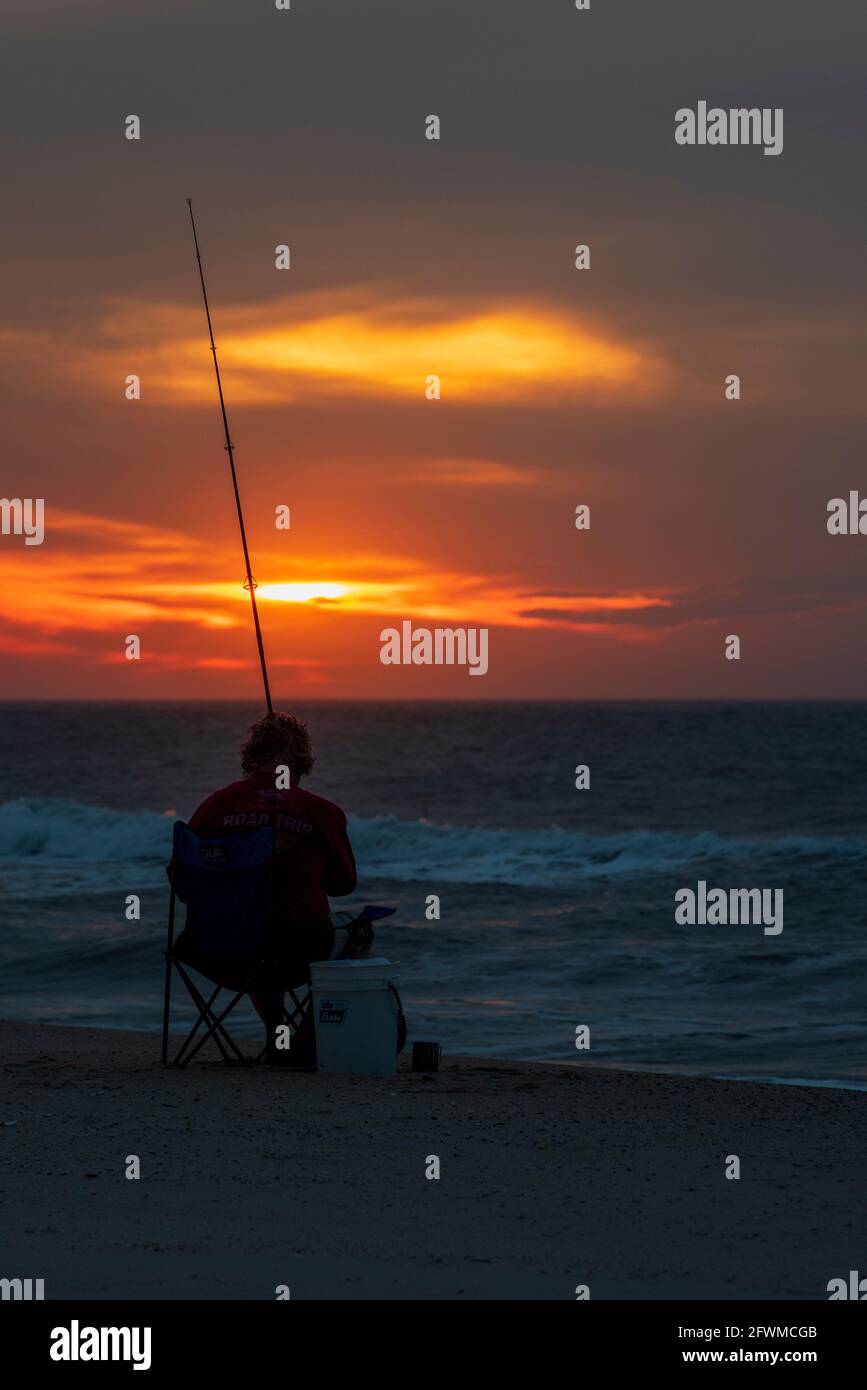Un uomo pesca nel surf all'alba sull'isola di Assateague National Seashore. Foto Stock