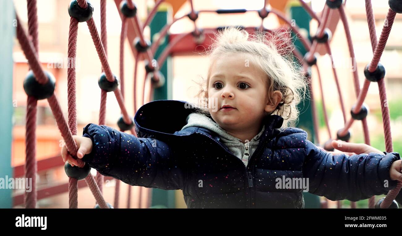 Vista frontale di un bambino biondo che si diverte sul parco giochi. Foto Stock