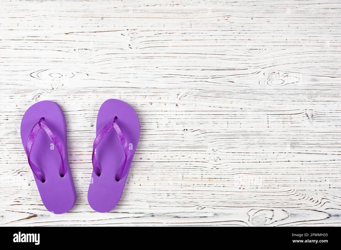 ciabatte in gomma viola su sfondo bianco in legno, vista dall'alto, posto per il testo Foto Stock