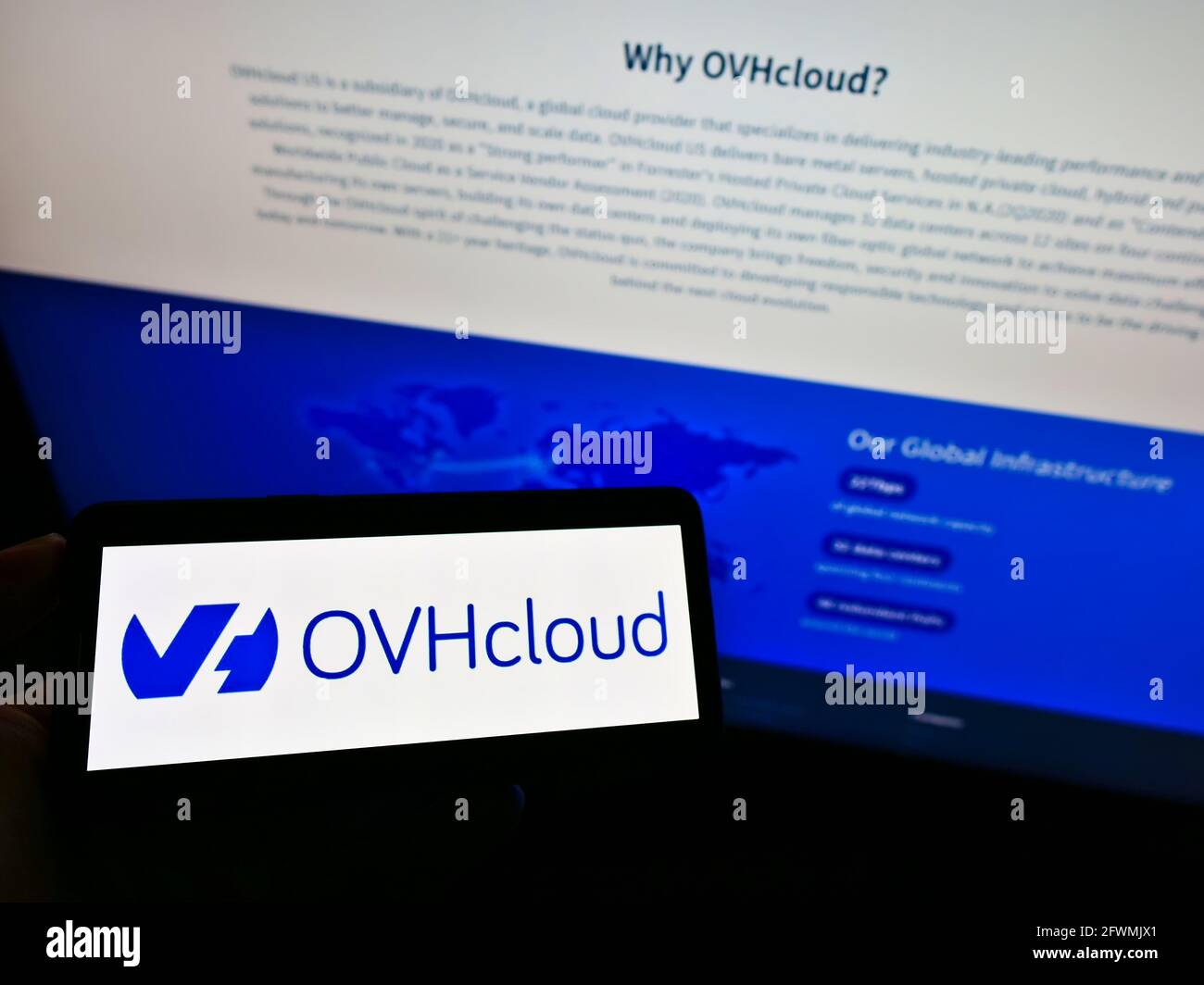 Persona che detiene il cellulare con il logo della società francese di cloud computing OVH Groupe SAS sullo schermo di fronte alla pagina web aziendale. Mettere a fuoco il display del telefono. Foto Stock