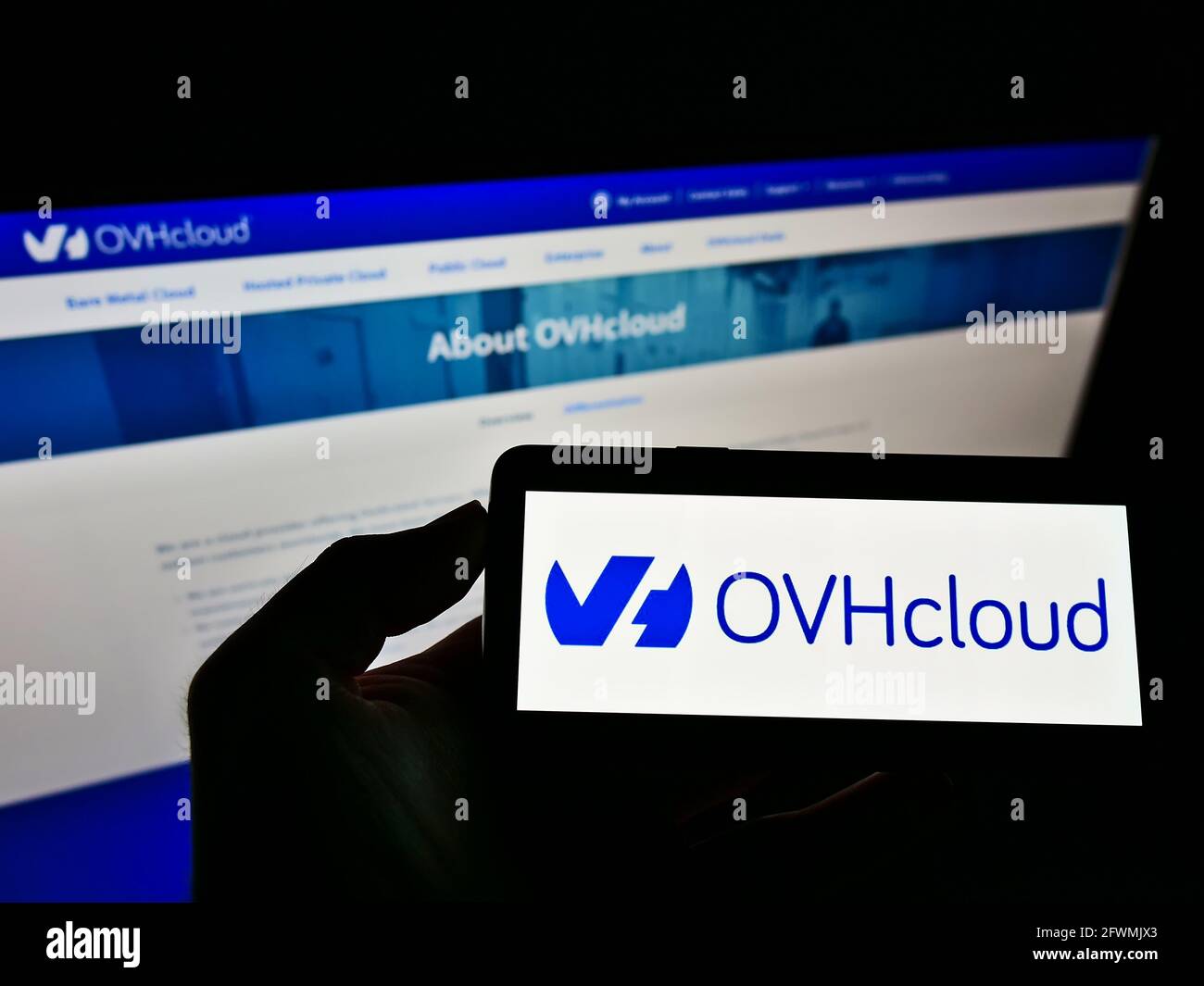 Persona che detiene il cellulare con il logo aziendale della società francese di cloud computing OVH Groupe SAS sullo schermo davanti alla pagina web. Mettere a fuoco il display del telefono. Foto Stock