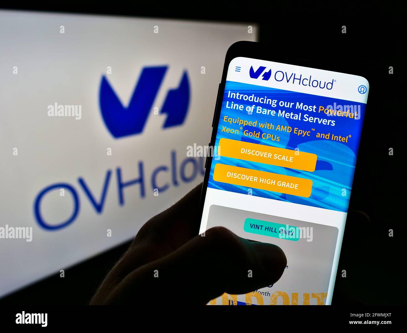 Persona in possesso di smartphone con sito web della società francese di cloud computing OVH Groupe SAS sullo schermo davanti al logo. Mettere a fuoco il centro del display del telefono. Foto Stock
