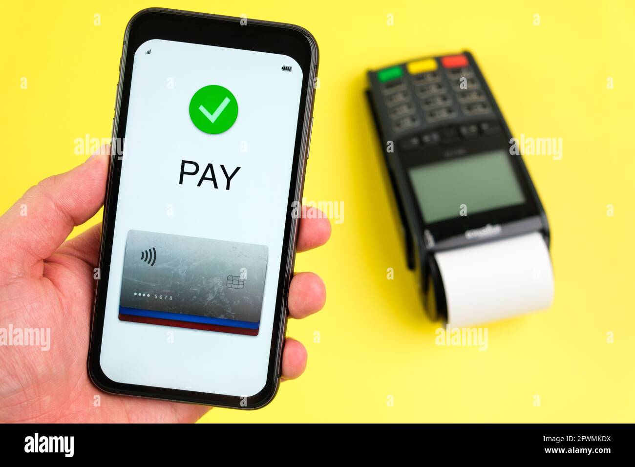 Applicazione di pagamento senza contatto sullo schermo dello smartphone e del terminale pos su sfondo giallo. Foto Stock