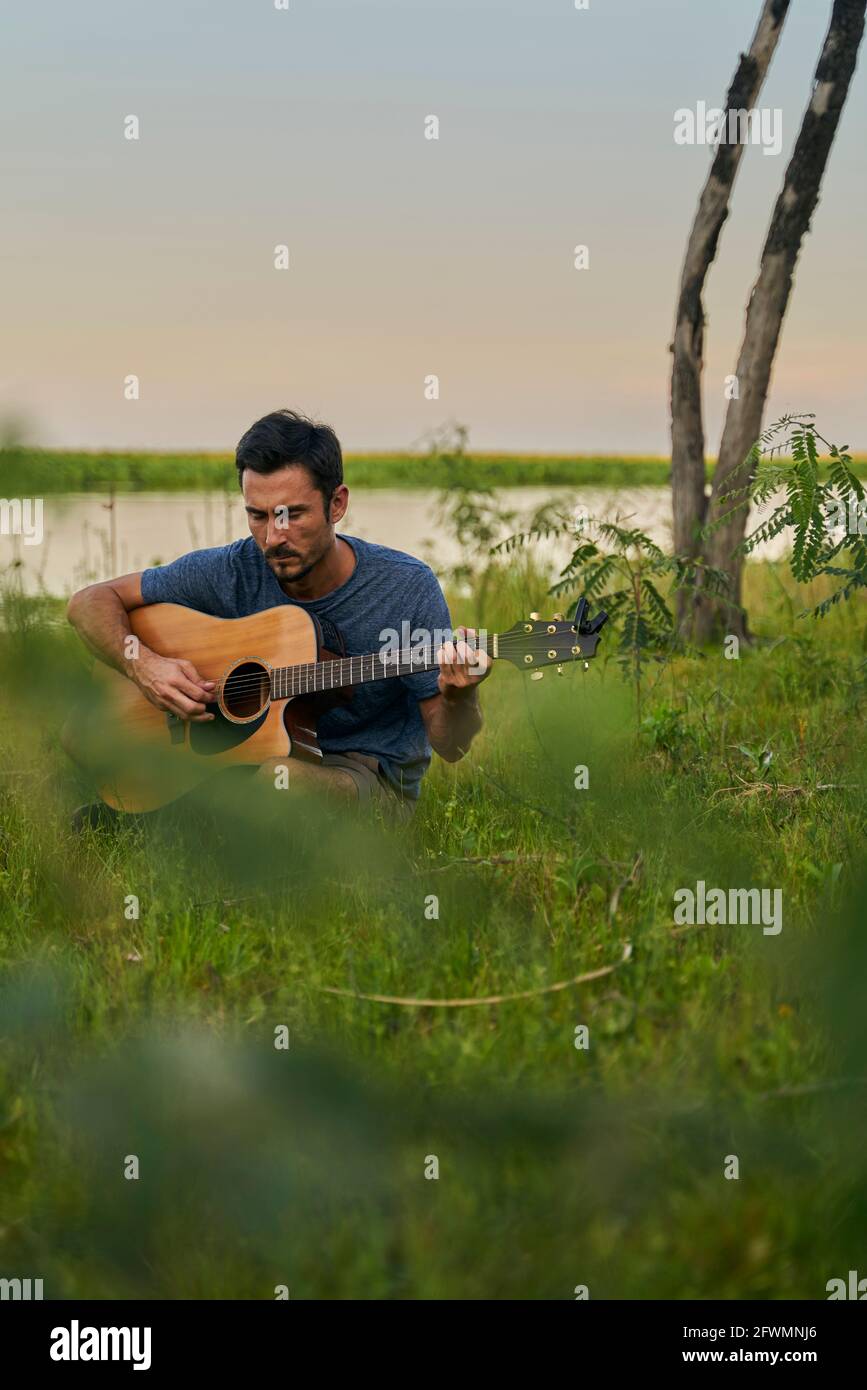 ritratto di giovane musicista che suona la chitarra al tramonto Foto Stock