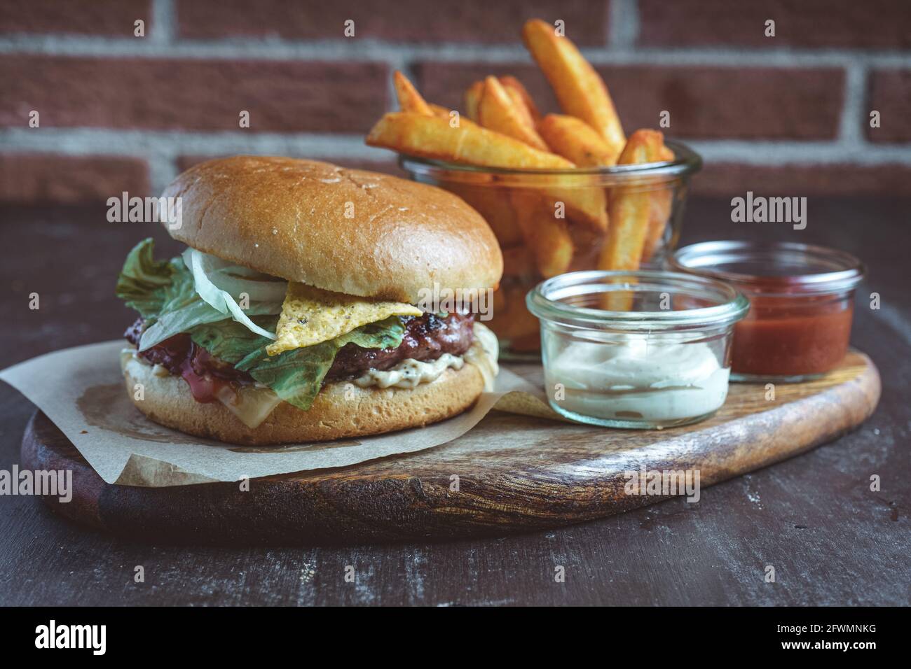 Primo piano di hamburger con nachos e patatine fritte serviti asse di legno Foto Stock