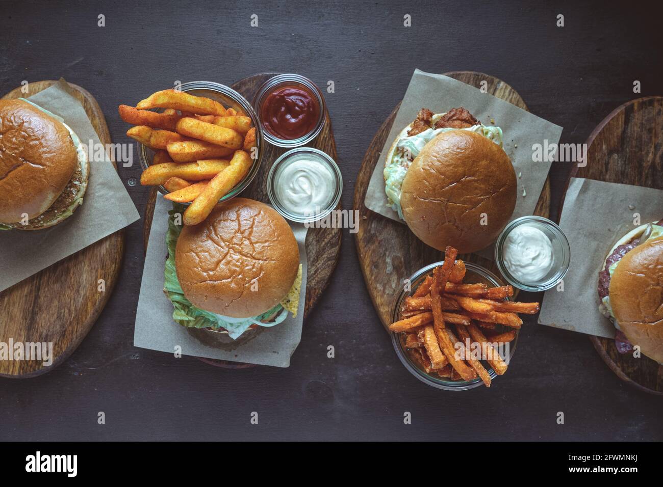 Vista ad alto angolo di vari hamburger con patatine fritte servite su tavole di legno Foto Stock