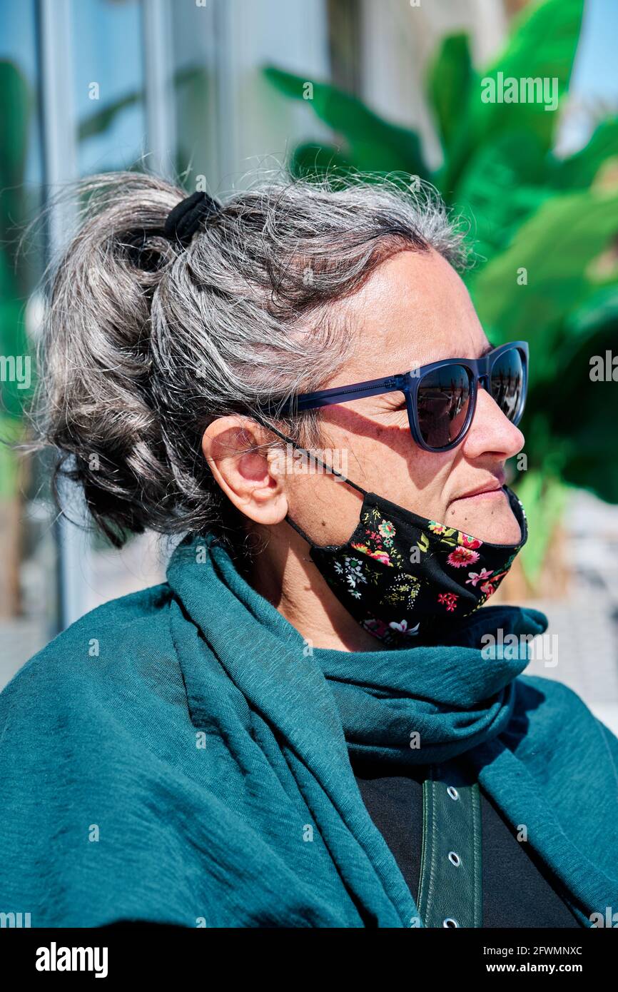 Ritratto di una donna di mezza età con capelli bianchi, occhiali da sole e  una maschera sotto la bocca Foto stock - Alamy