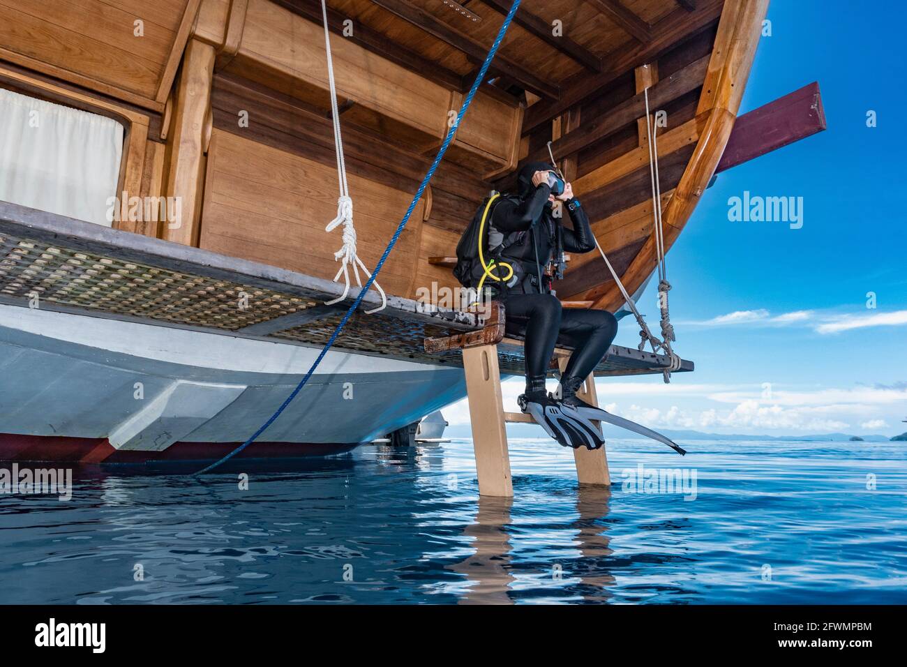 donna che si prepara a tuffarsi da una barca a vela dentro Raja Ampat Foto Stock
