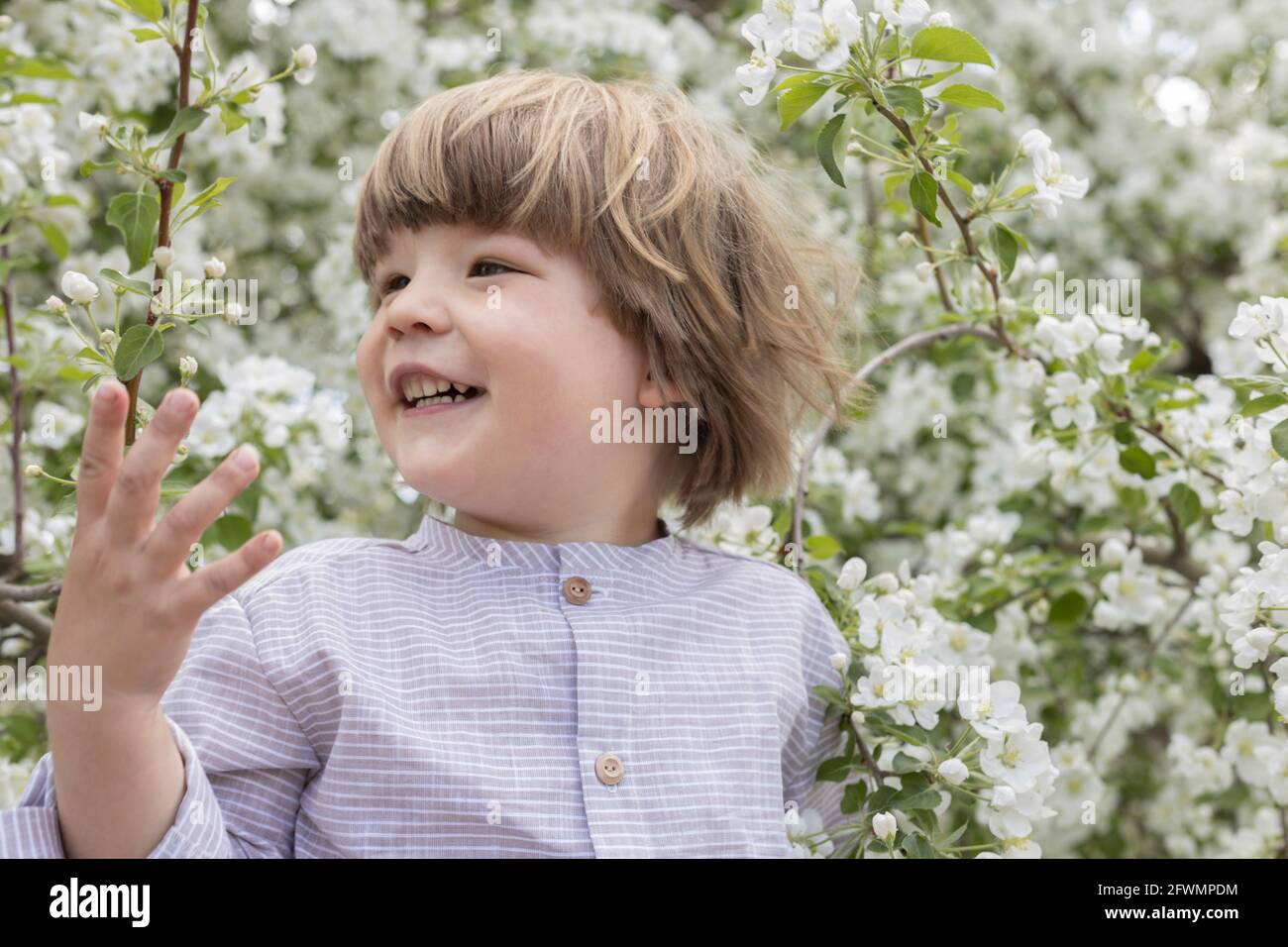 Primo piano sorridente bambino tra fiori bianchi che fioriscono nel giardino Foto Stock