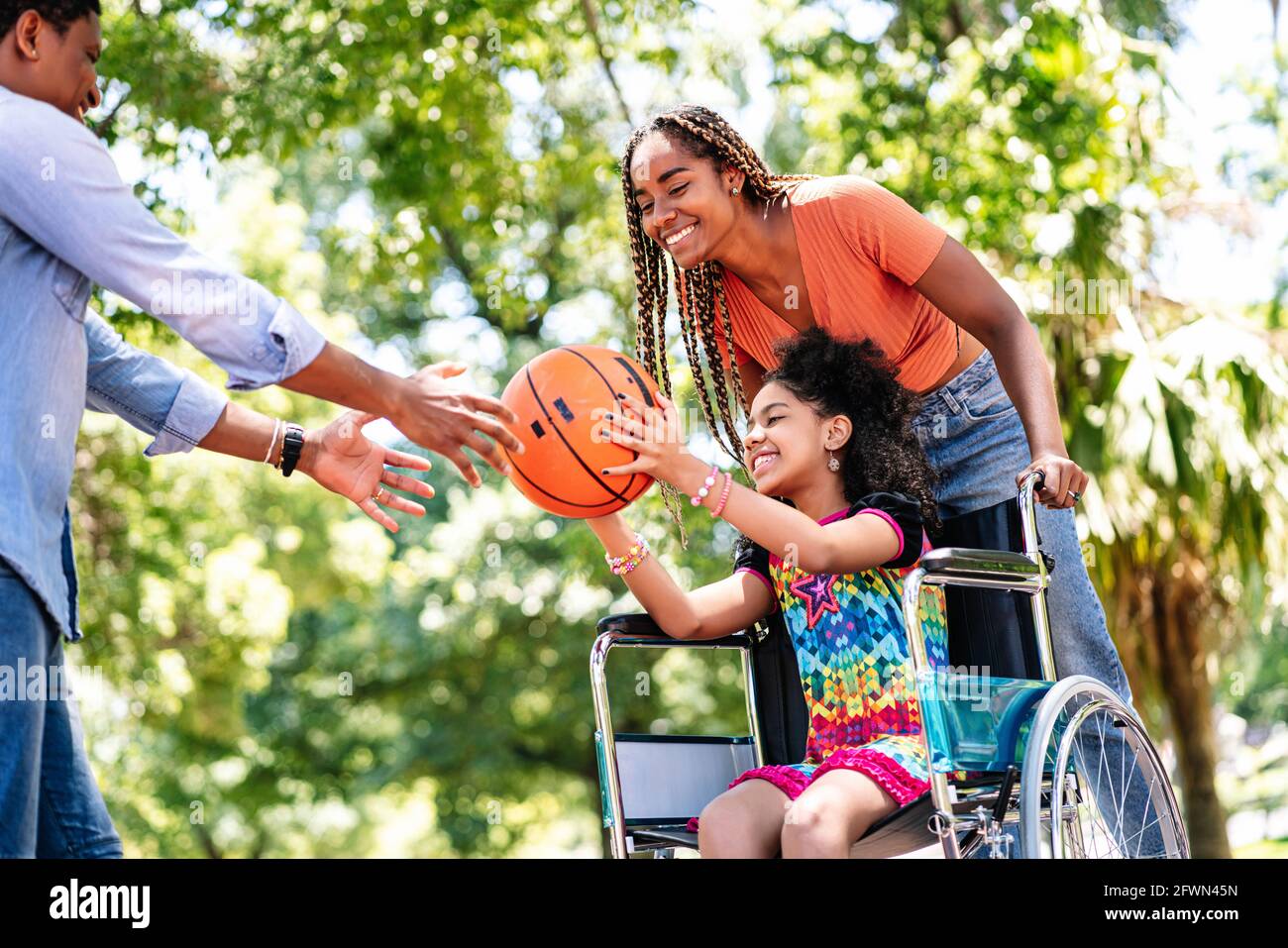 Ragazza in sedia a rotelle che gioca a basket con la sua famiglia. Foto Stock