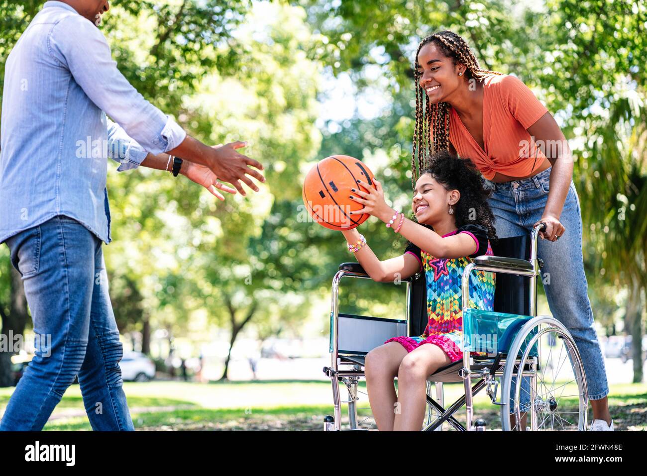 Ragazza in sedia a rotelle che gioca a basket con la sua famiglia. Foto Stock