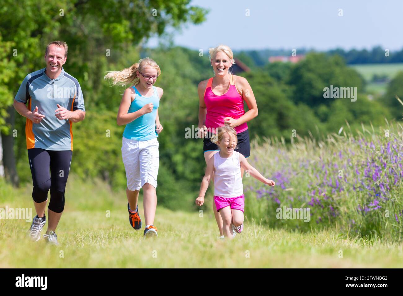 I genitori con due bambini sport correndo all'aperto Foto Stock