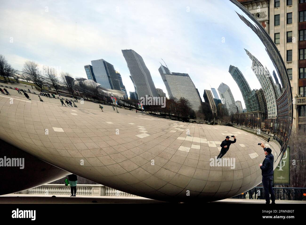 Chicago, Illinois, Stati Uniti. Un uomo isolato prende un selfie del suo proprio riflesso e una parte dello skyline della città vicino alla scultura "Cloud Gate". Foto Stock