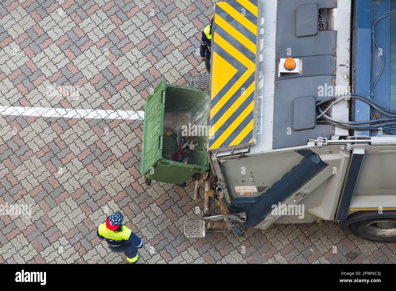 Vista aerea di un carrello per rifiuti che utilizza l'alimentazione idraulica per sollevare il contenitore per scaricare i rifiuti all'interno, sono necessari solo due operatori per lavorare. Foto Stock