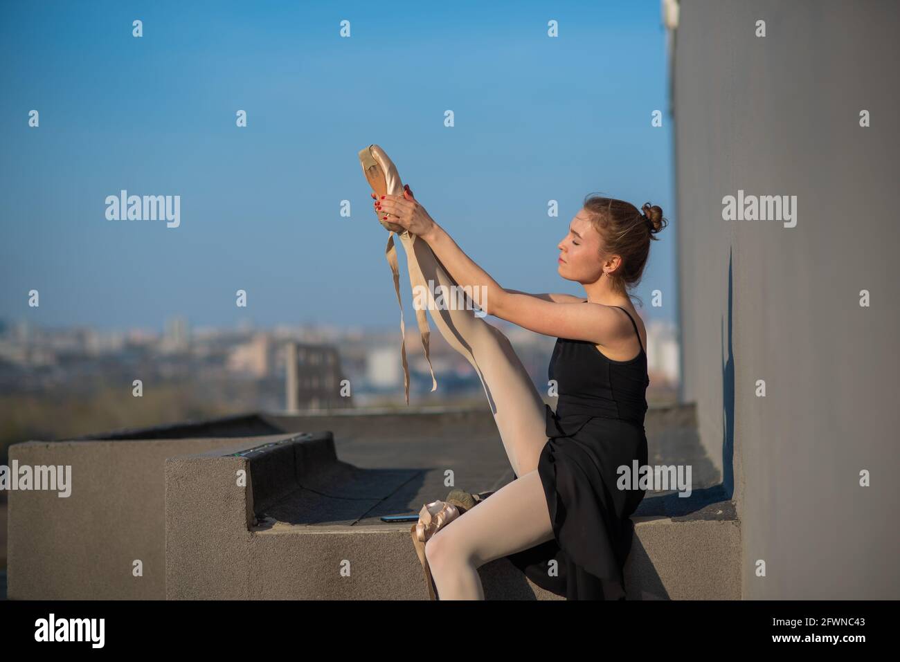 Ballerina in un tutu in posa vicino alla recinzione. Bella giovane donna che indossa un abito nero e scarpe appuntite all'esterno. Ballerina bellissima Foto Stock