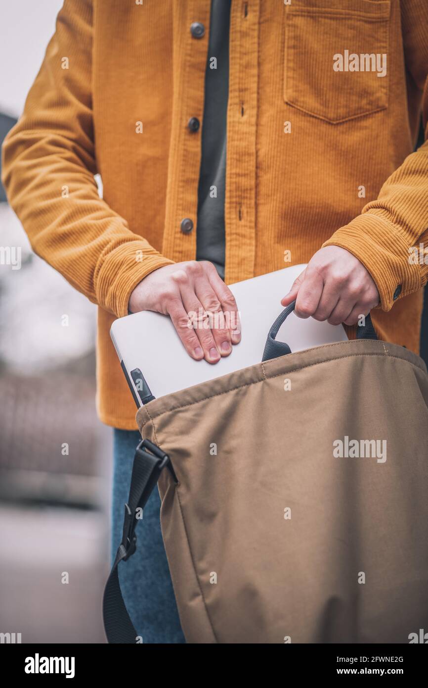 Primo piano di mans Hand mettendo il laptop in una borsa Foto Stock