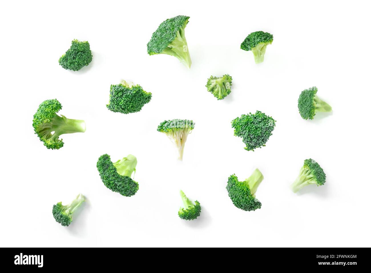 Fiori di broccoli che cadono su uno sfondo bianco. Tagliare pezzi di broccoli verdi, isolati, il concetto di una dieta vegetale sana Foto Stock