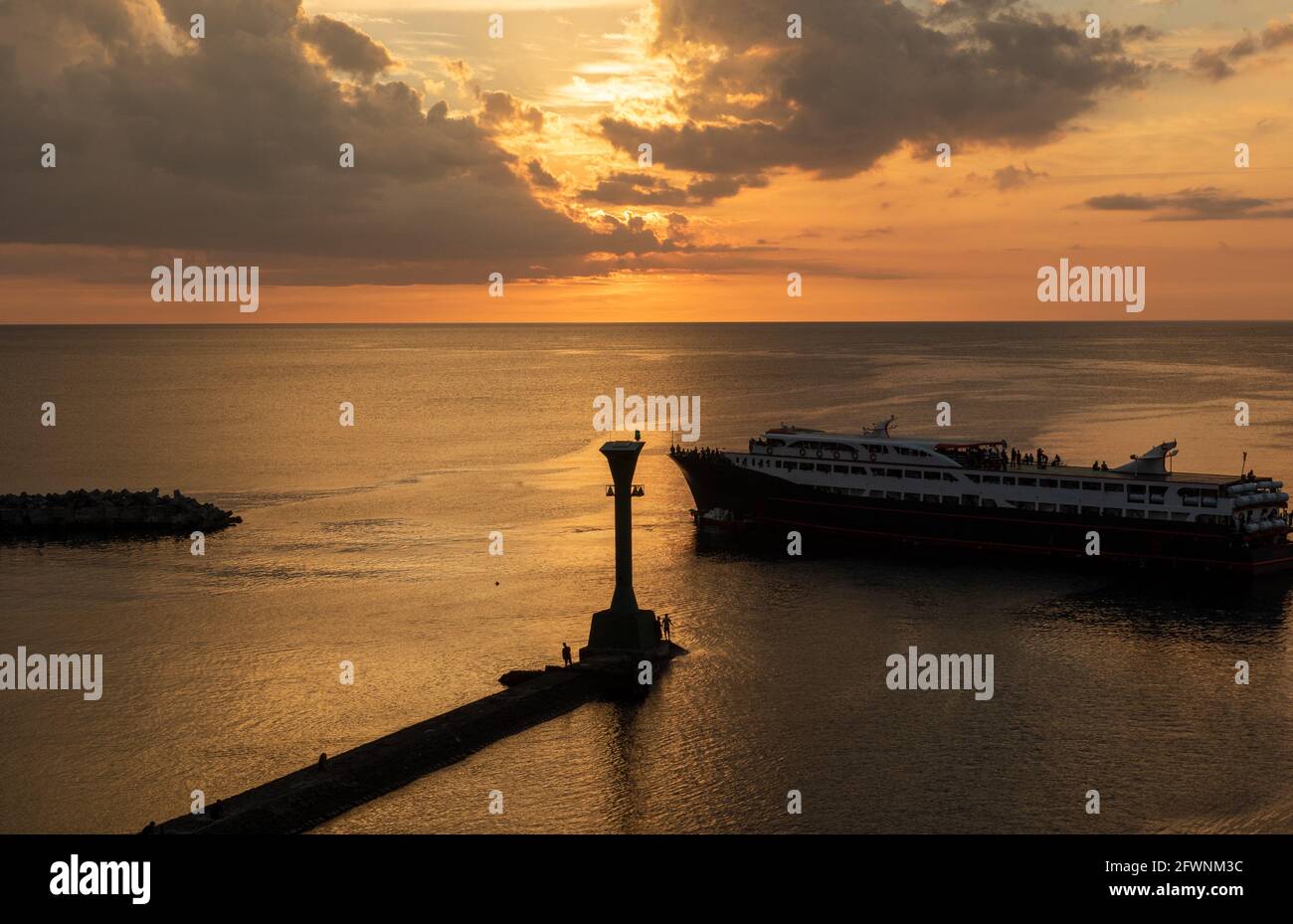 Faro al tramonto, le navi passano attraverso il porto Foto Stock