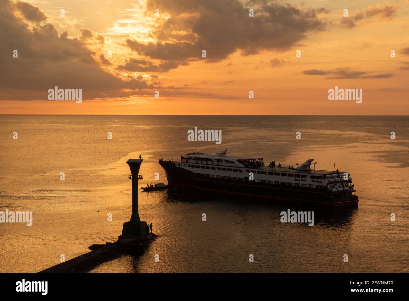 Faro al tramonto, le navi passano attraverso il porto Foto Stock
