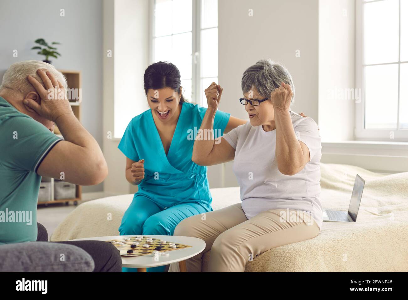 Felici pazienti anziani in pensione insieme con infermiere che gioca a scacchi e. divertirsi Foto Stock