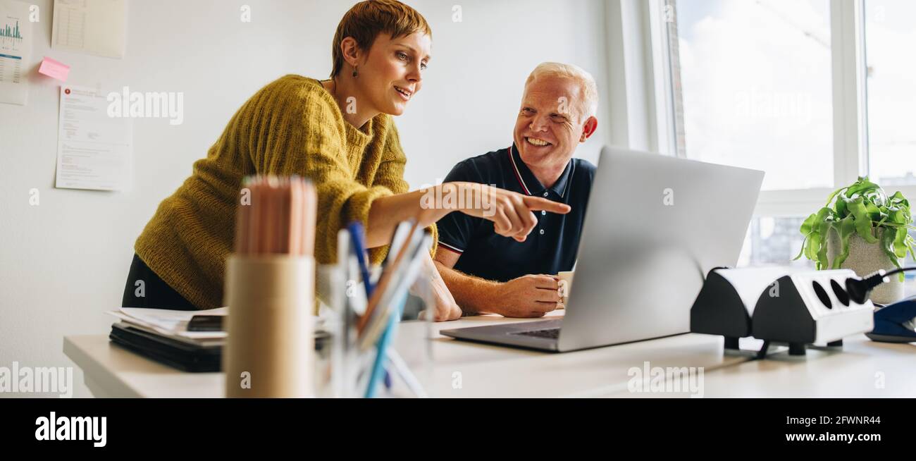 Sorridente uomo e donna in ufficio che discute di progetto. La tecnologia come parte della vita lavorativa. Foto Stock