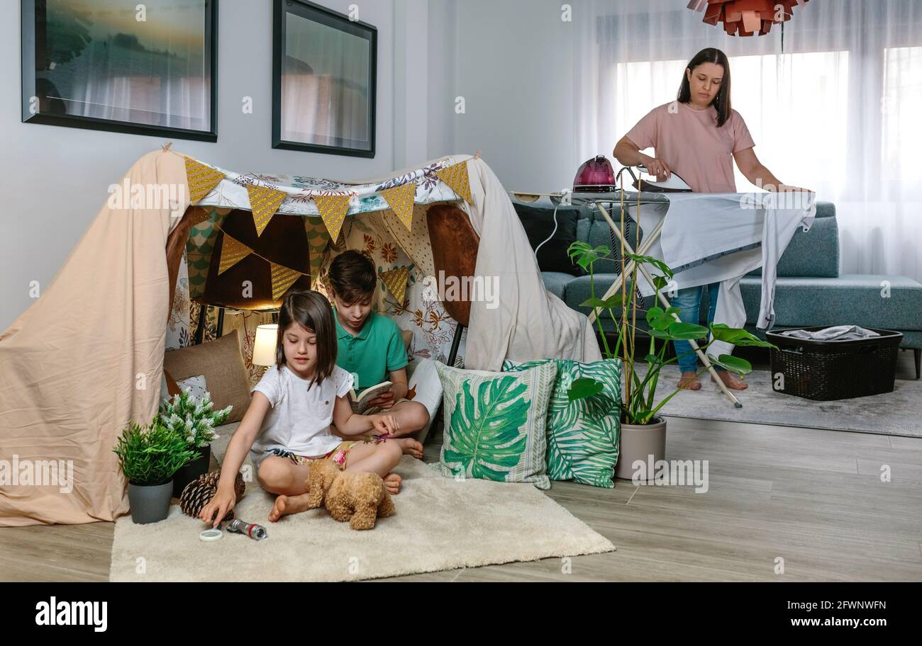 La madre stira mentre i suoi bambini giocano in campeggio a casa Foto Stock