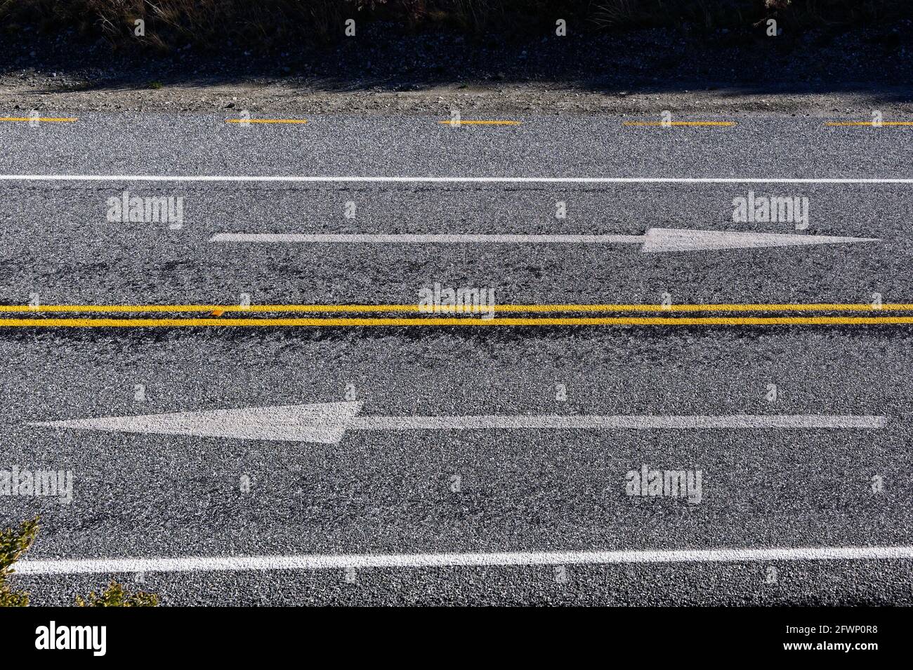 Le frecce che indicano la direzione di guida sono dipinte su una strada in Nuova Zelanda che si trova sul lato sinistro della strada. In che modo. Foto Stock