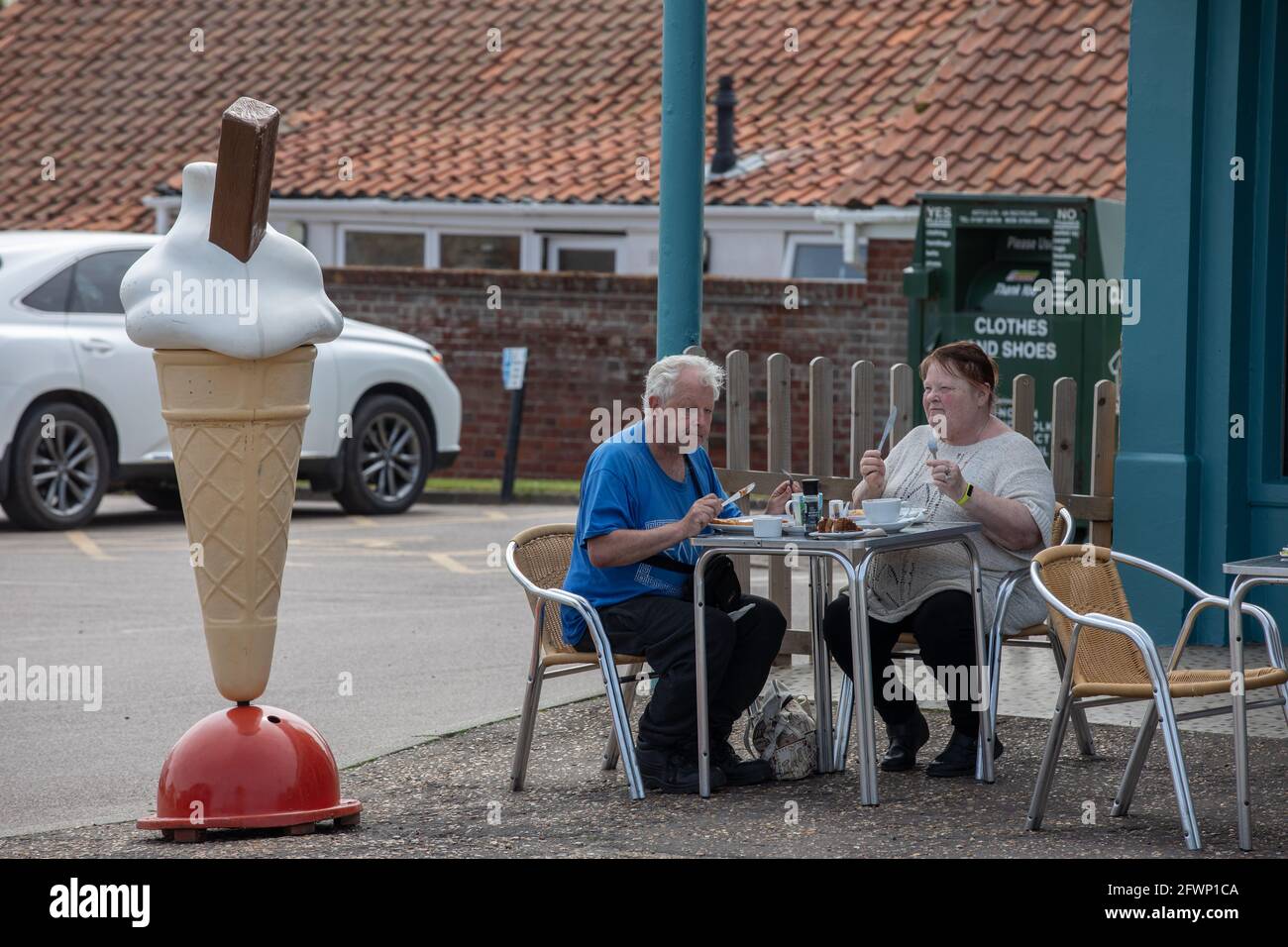 Una coppia mangia pranzo fuori del Beach Hut cafe, Mundesley, North Norfolk, Inghilterra, Regno Unito Foto Stock
