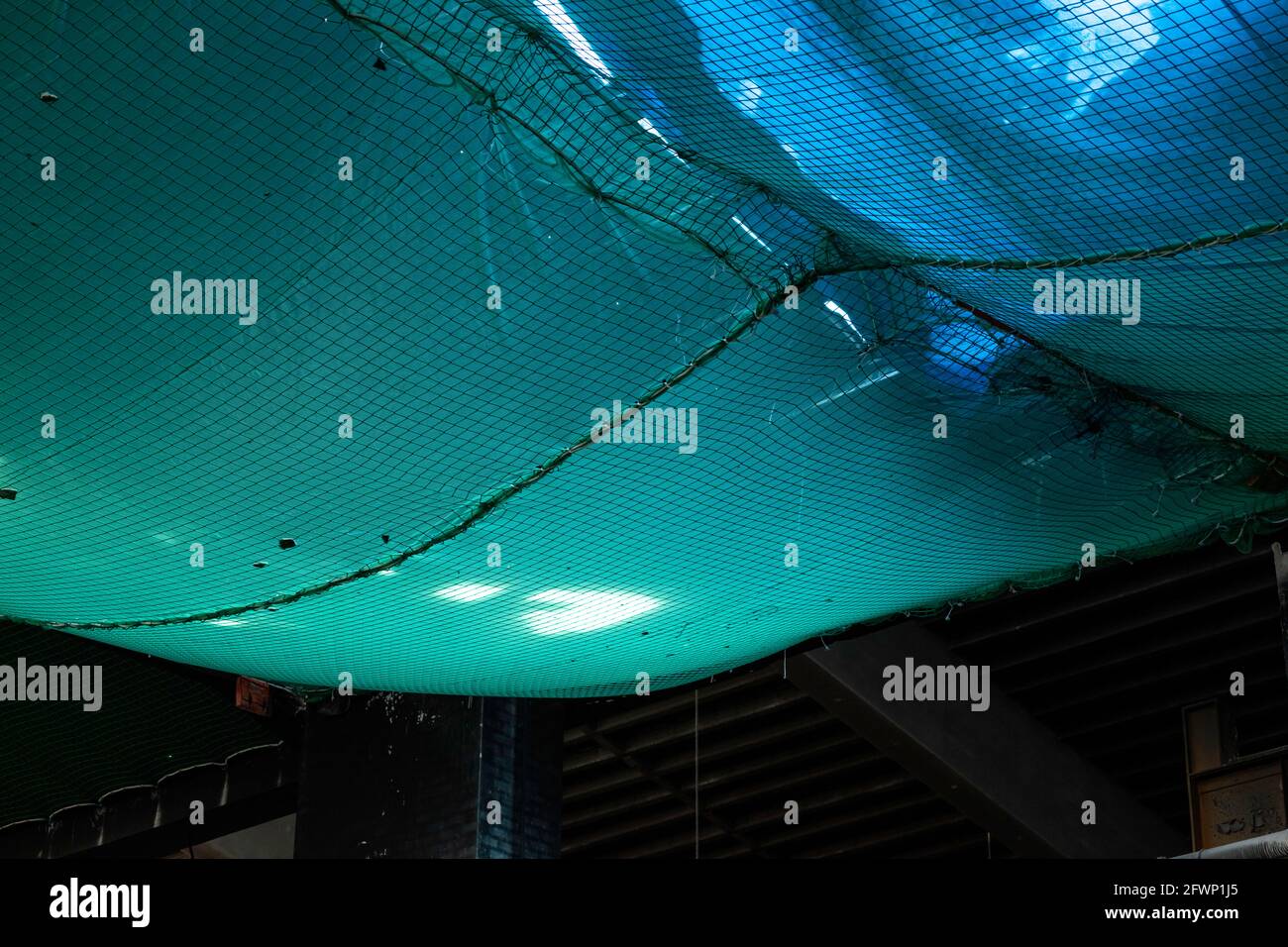 una rete di sicurezza di colore verde, posta sotto il tetto per evitare il rischio di cadute durante i lavori Foto Stock