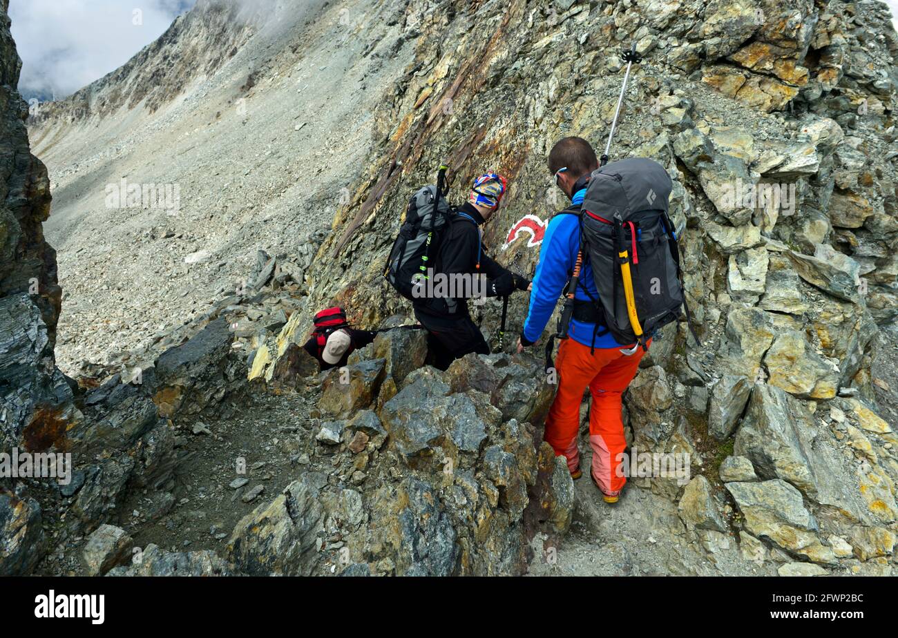Alpinisti in uno stretto passaggio roccioso al Passo del Tracuit, col de Tracuit, Zinal, Val d’Anniviers, Vallese, Svizzera Foto Stock