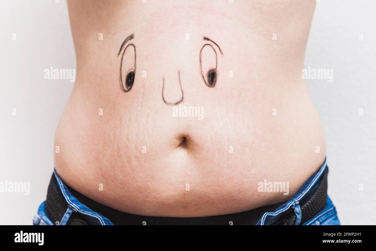 Una faccia divertente dipinta sul ventre di un uomo grasso irriconoscibile. Gli occhi e il naso sono dipinti, e la bocca è l'ombelico. Foto Stock