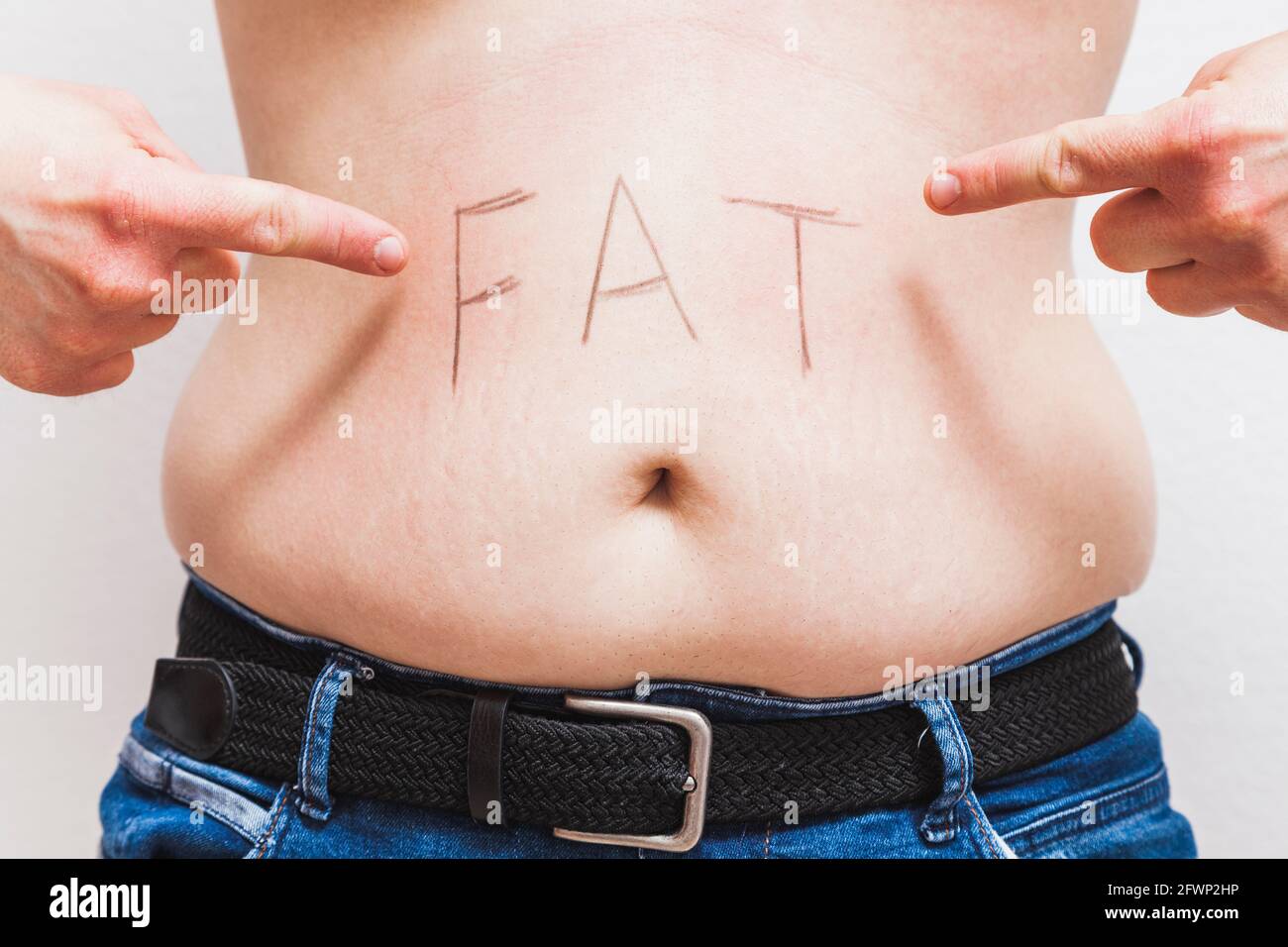 Un uomo grasso irriconoscibile che punta con le sue due dita indice al suo ventre dove la parola 'grasso' è scritta sopra il suo ombelico. Foto Stock