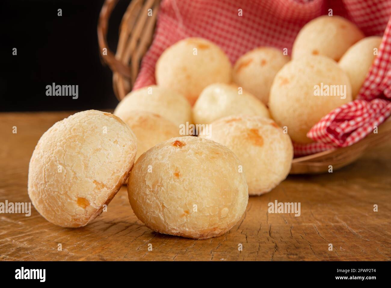 Pane al formaggio brasiliano, cesto con stoffa a scacchi con pane al formaggio su legno rustico, fuoco selettivo. Foto Stock