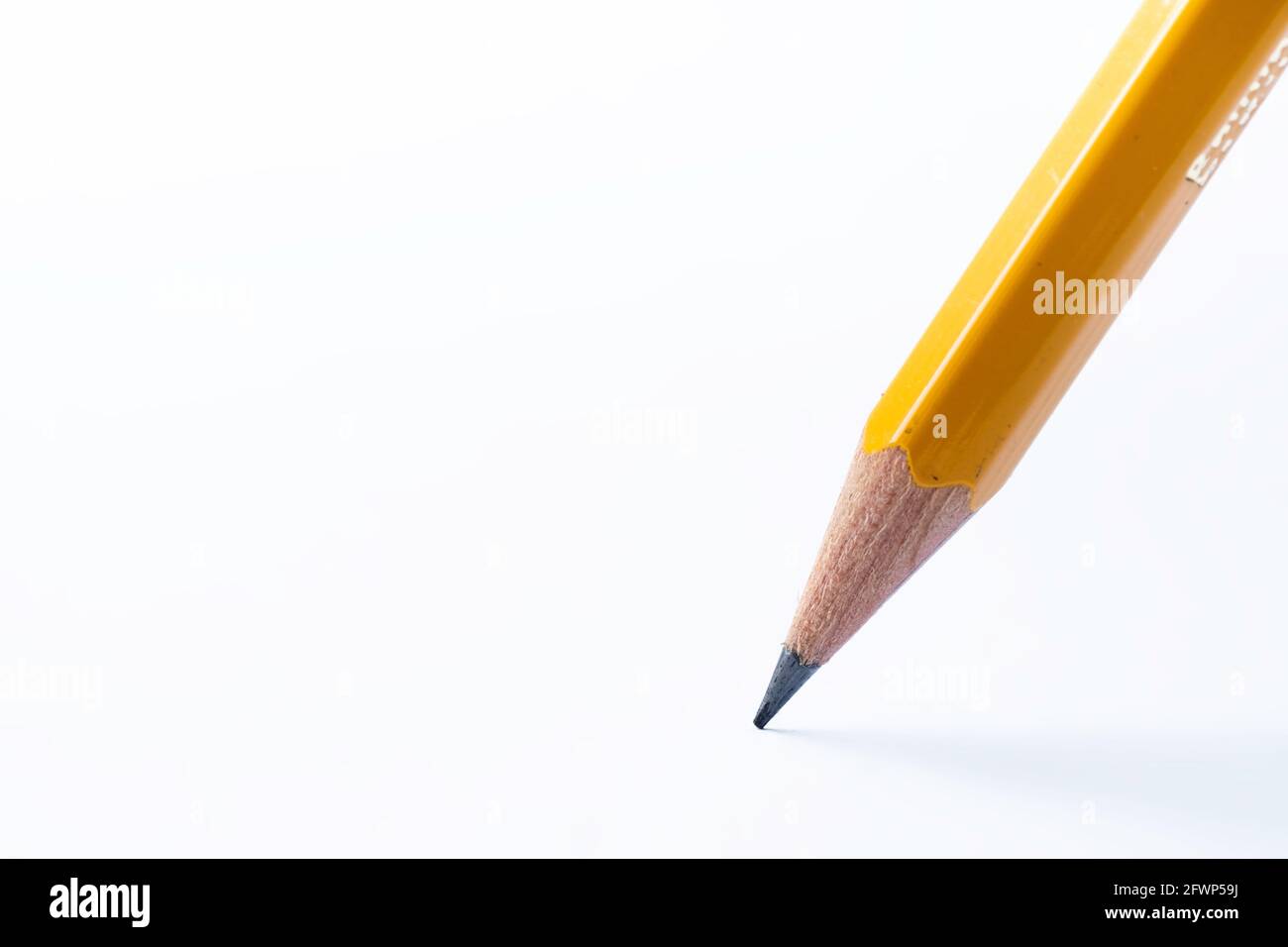 Matita si trova su carta bianca. Il punto acuto è stato appena affilato. Mettere a fuoco la punta di grafite nera. Immagine di sfondo Foto Stock