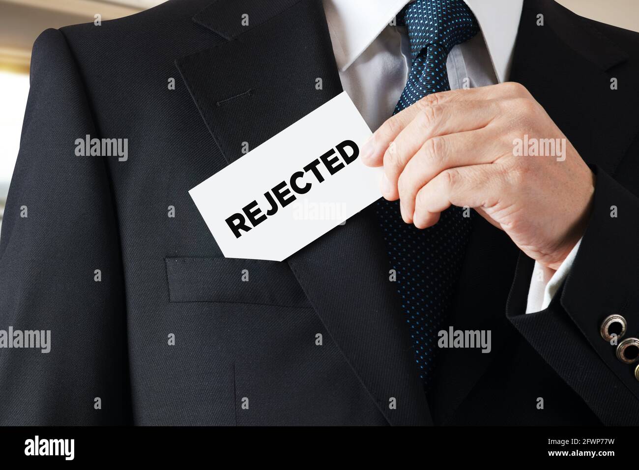 L'uomo d'affari toglie un biglietto da visita dalla sua tasca con la parola rifiutato Contratto, progetto, piano o rifiuto dell'applicazione o rifiuto. Foto Stock