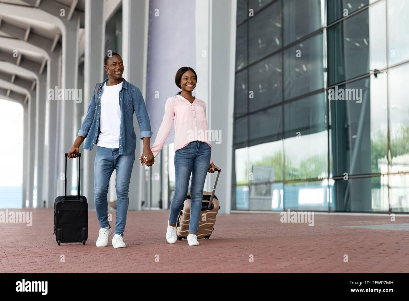 Viaggio di vacanza. Ritratto di felice coppia africana Passeggiate con valigie vicino aeroporto Foto Stock