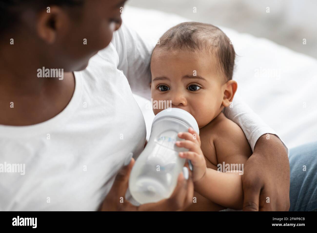 Donna afroamericana che alimenta il suo bambino dal biberon Foto Stock