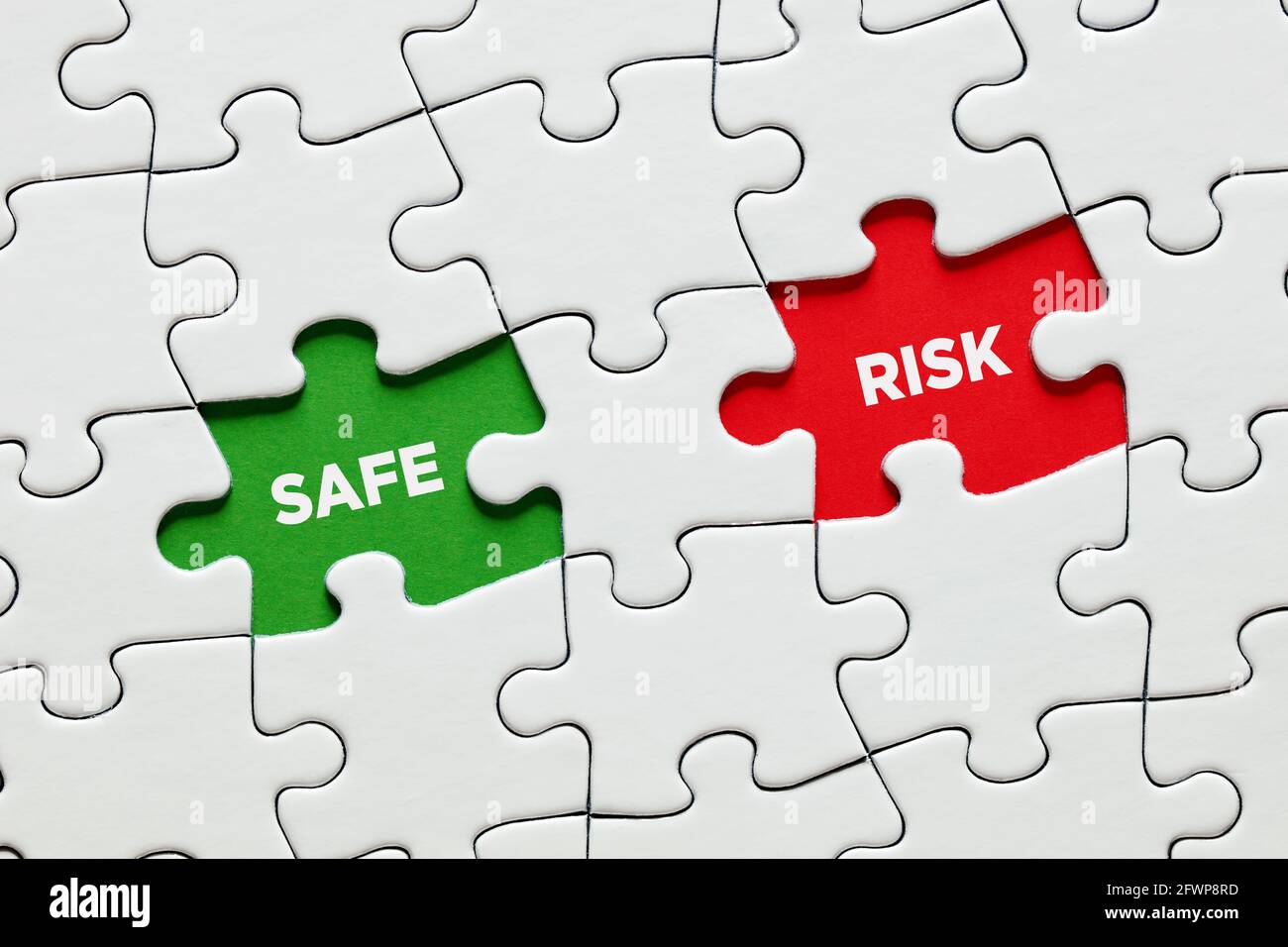 Pezzi di puzzle mancanti con le parole rischio e sicuro. Concetto di decisione di investimento aziendale tra assunzione di rischi o scommessa sicura. Foto Stock
