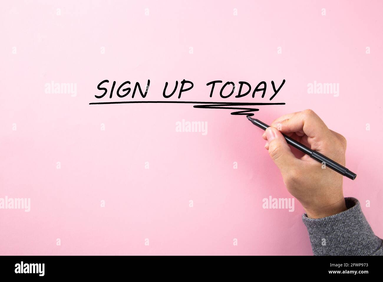 Mano che scrive un SEGNO di parola OGGI su sfondo rosa. Foto Stock