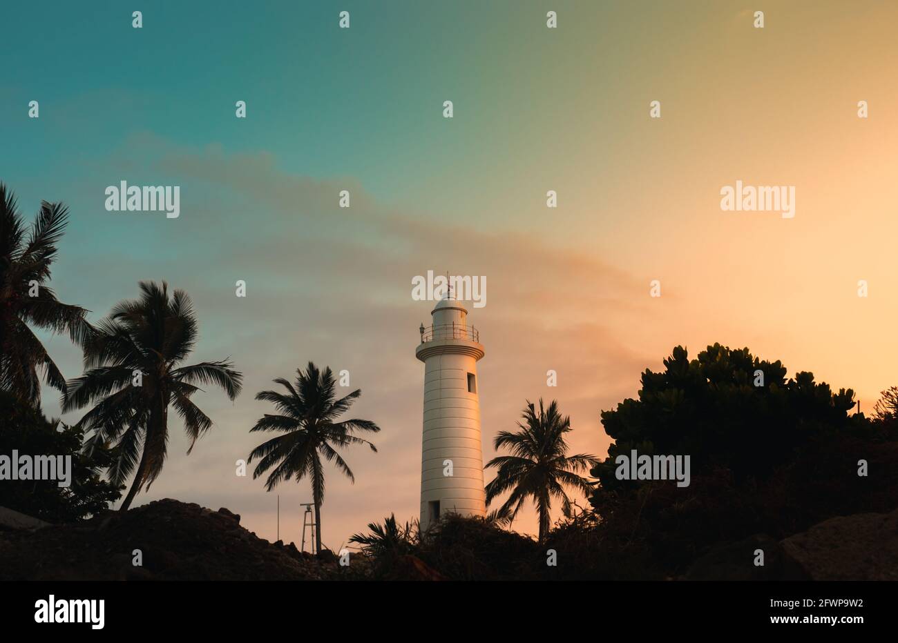 Faro che si illumina al tramonto serale, fortezza olandese Galle, palme, e la foto panoramica del paesaggio costo. La stazione di luce più antica dello Sri Lanka e. Foto Stock