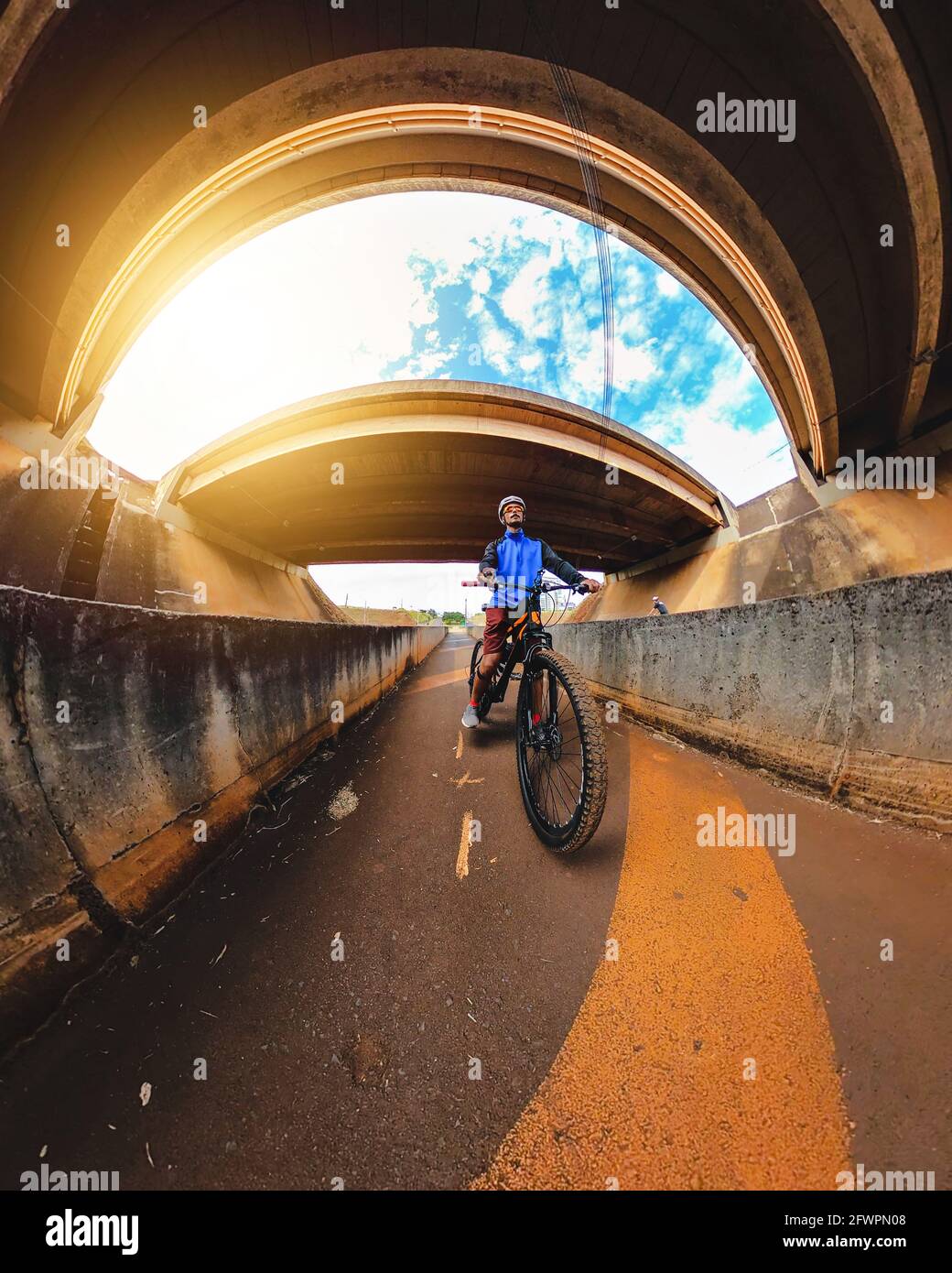 Uomo nero allegro con la bicicletta che va per un giro in centro, guardando la macchina fotografica nel sole che tramonta. Lifestyle Riding Bike Outdoor Concept image. Foto Stock