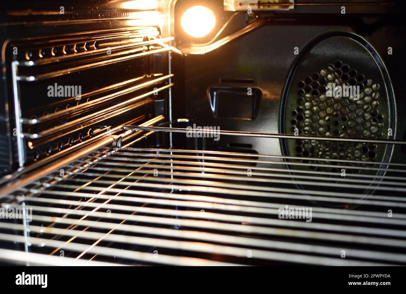 Una vista dell'interno di un forno vuoto con una lampadina di illuminazione e una rastrelliera metallica. Foto Stock