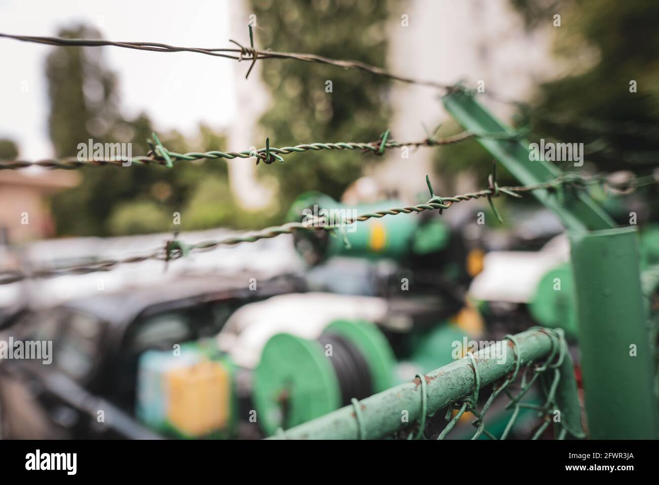 Dettagli della profondità di campo poco profonda (fuoco selettivo) con filo spinato intorno a una struttura. Foto Stock