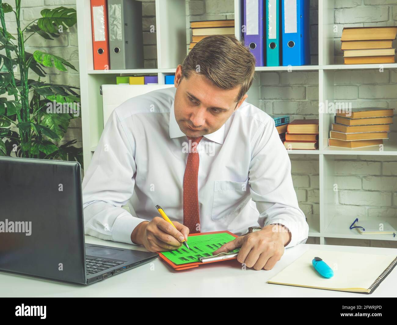 Il dipendente concentrato verifica i dati su un notebook. L'uomo d'affari lavora con il rapporto. Foto Stock