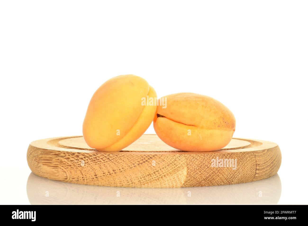 Due succulente albicocche di ananas su un vassoio di legno, primo piano, isolate su bianco. Foto Stock