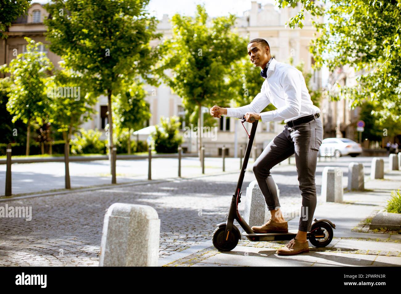 Bel giovane afroamericano con scooter elettrico su una strada Foto Stock