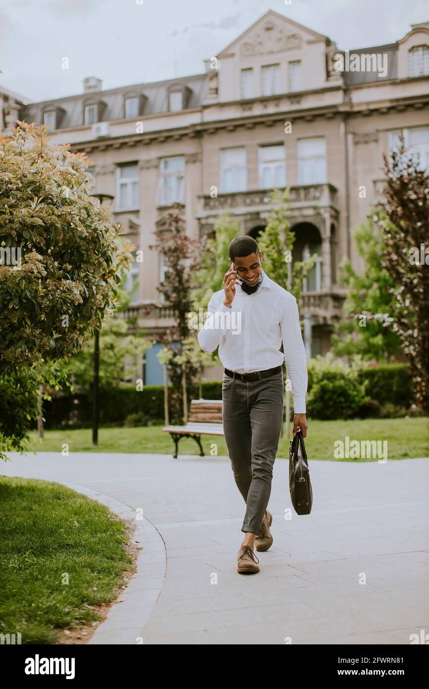 Bel giovane uomo d'affari afro-americano che usa un cellulare su una strada Foto Stock