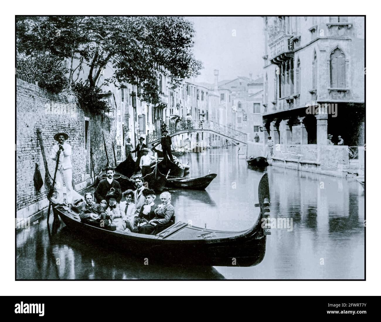 Venezia d'epoca del 1900 gruppo di turisti che posano su una gondola per fotografare formalmente Venezia, c. 1900. BIANCO E NERO Foto Stock