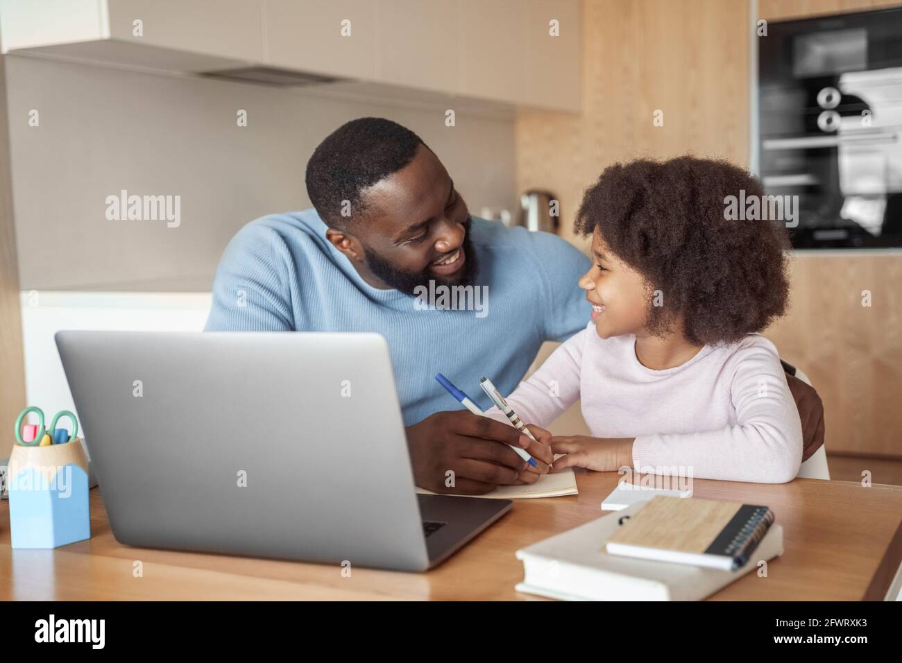 Felice giovane padre genitore aiutare la figlia del bambino con imparare a distanza da casa Foto Stock