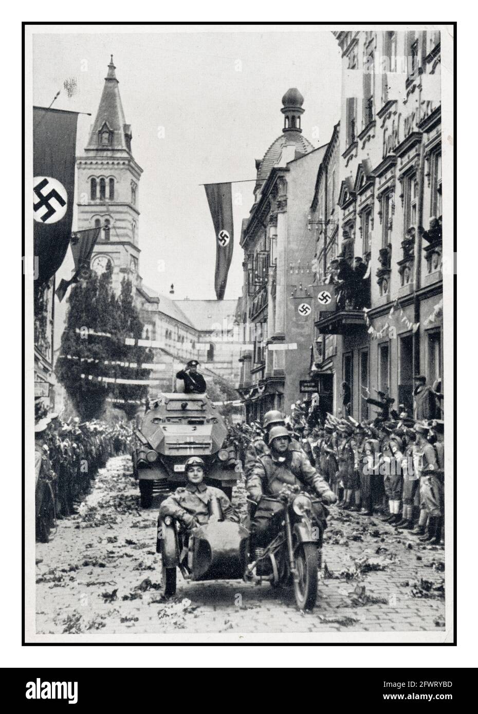 SUDETENLAND 1938 sfilata militare nazista a Kraslice (Graslitz) dopo l'annessione della Sudetenland nell'ottobre 1938 alcuni residenti locali accolgono i nazisti con bandiere, bandiere e fiori Swastika gettati sulla strada Foto Stock